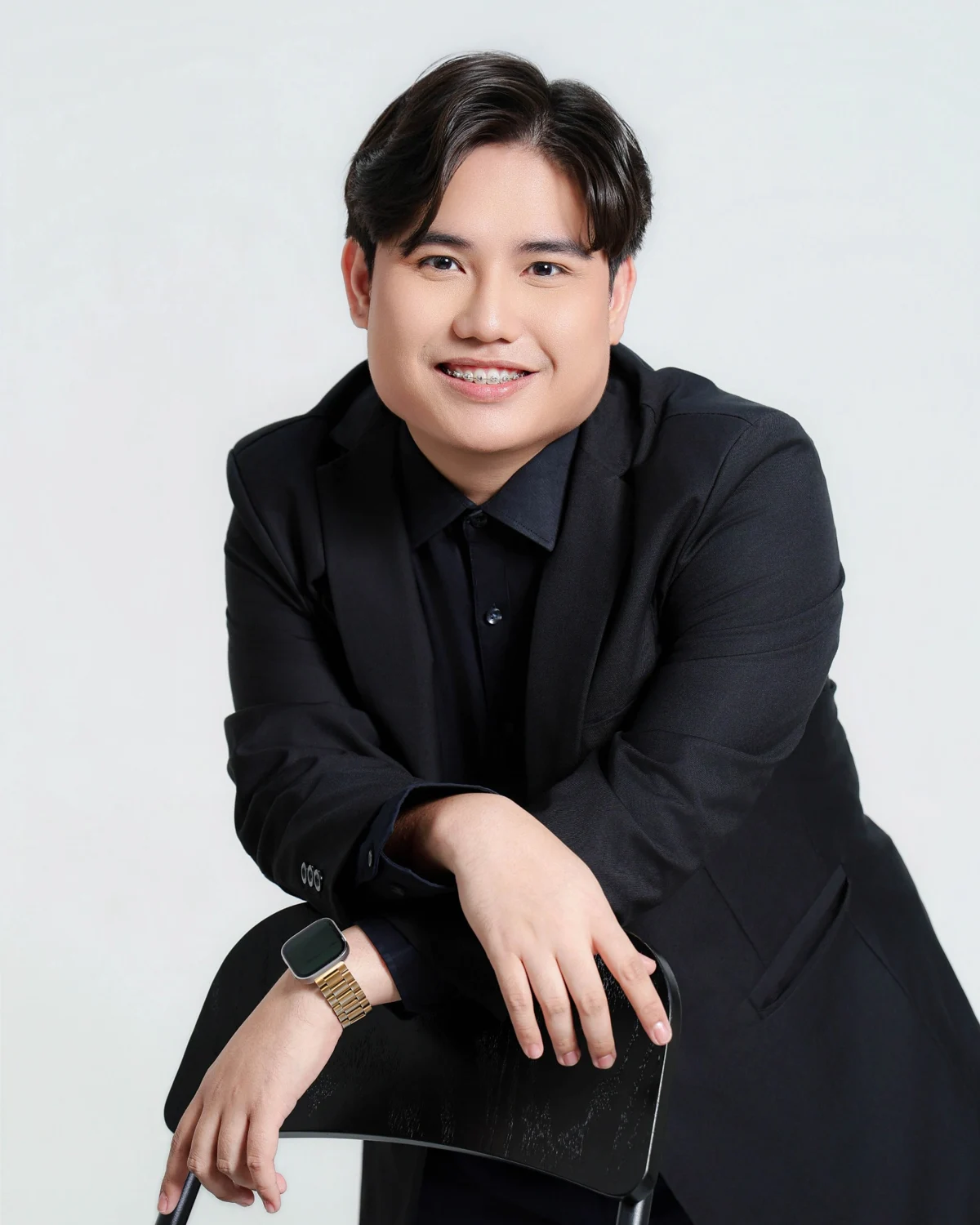 Brian Saludo smiling, seated in a black suit